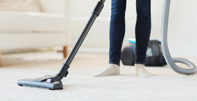Women cleaning living room white carpet with vacuum 